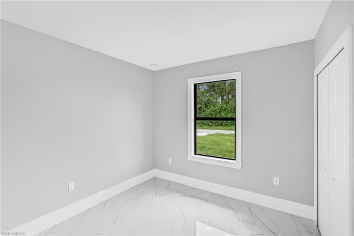 Unfurnished bedroom featuring light marble finish floors and a closet