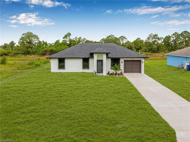 Prairie-style house with driveway, a front lawn, a garage, stucco siding, and a shingled roof