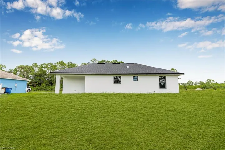 Back of house featuring a lawn and stucco siding