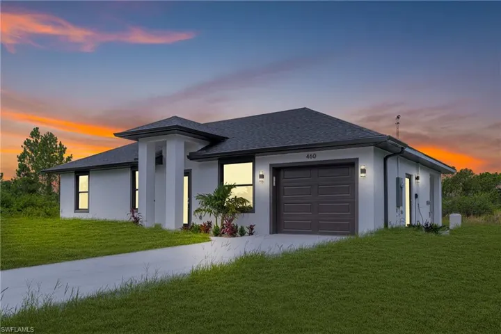 View of front of home with a garage, concrete driveway, a shingled roof, a lawn, and stucco siding