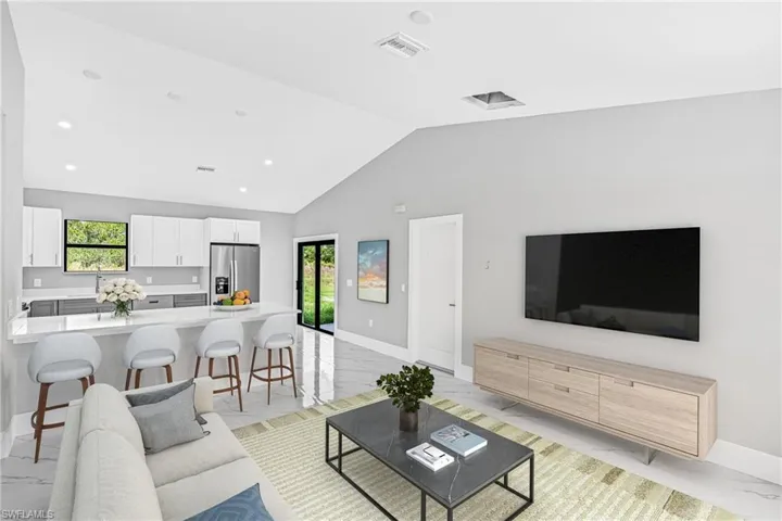 Living area with light marble finish flooring, lofted ceiling, healthy amount of natural light, and recessed lighting