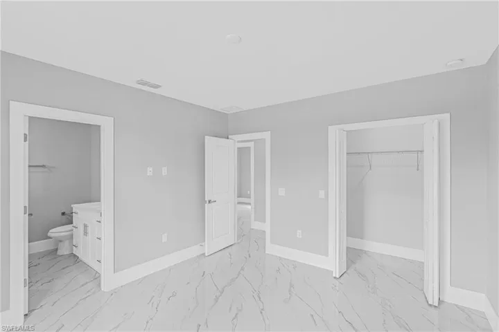 Unfurnished bedroom with light marble finish flooring and connected bathroom
