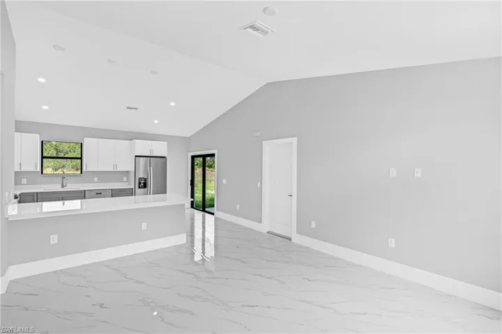 Kitchen with light marble finish floors, light countertops, appliances with stainless steel finishes, vaulted ceiling, and recessed lighting