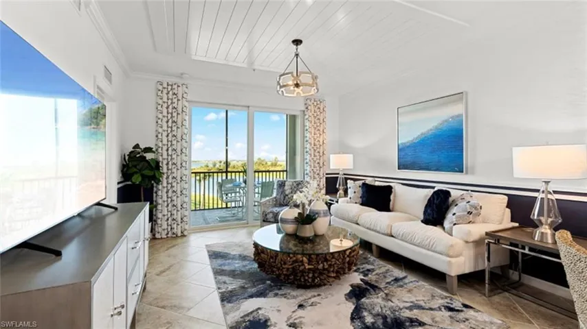 Living room featuring healthy amount of natural light, crown molding, light tile patterned flooring, and a chandelier