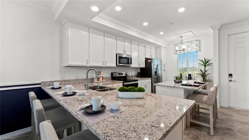 Kitchen featuring stainless steel appliances, crown molding, a peninsula, a kitchen breakfast bar, and white cabinets