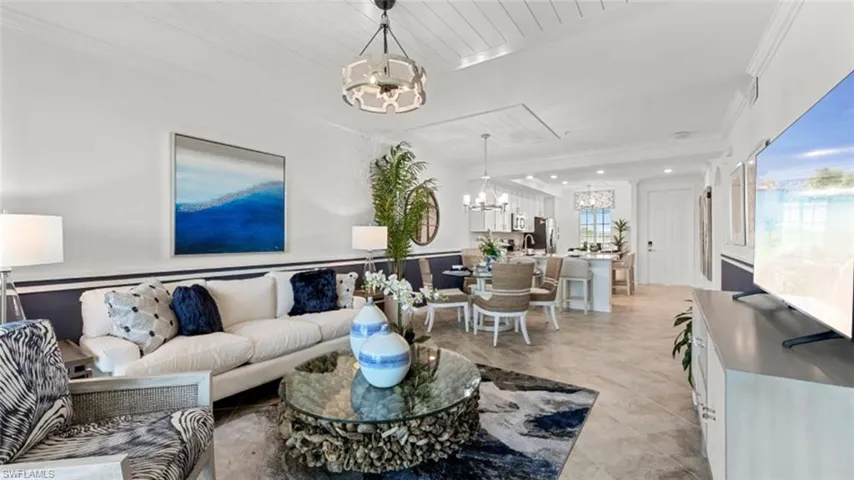 Living room featuring a chandelier, crown molding, and light tile patterned floors