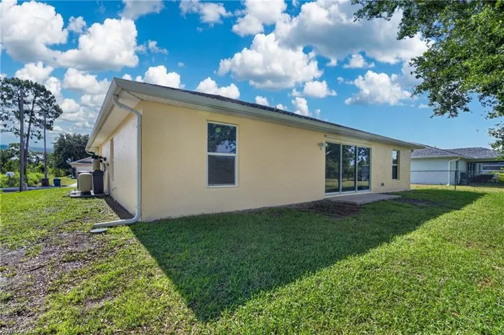 Rear exterior featuring stucco finish, a concrete patio, and sliding glass doors