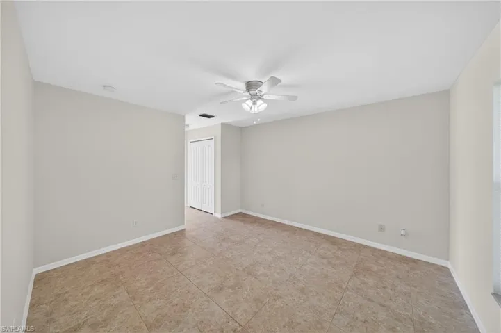 Spacious interior featuring neutral-toned walls, tile flooring, and a ceiling fan with integrated lighting