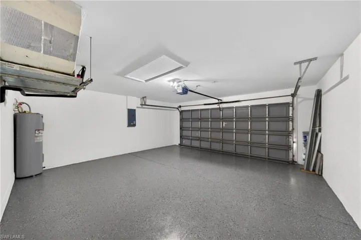 Spacious garage featuring a durable epoxy-coated floor, painted walls, automatic garage door opener, and overhead lighting