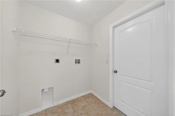 Laundry area featuring neutral wall paint, tile flooring, and a wire shelving unit