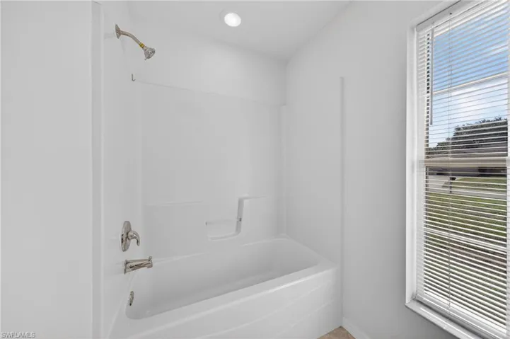 White tub and shower combination with brushed nickel fixtures