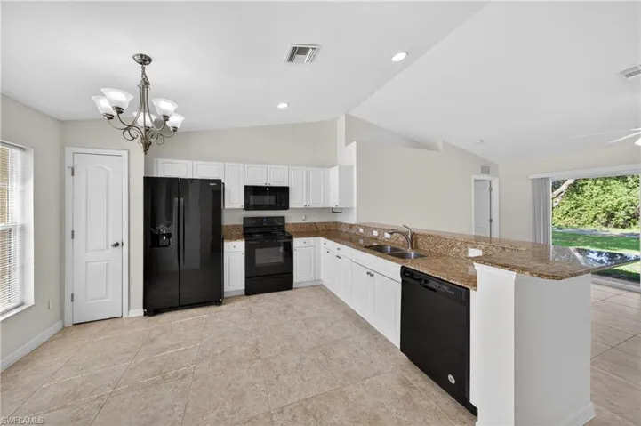 Kitchen featuring white cabinetry, granite countertops, black appliances, and tile flooring