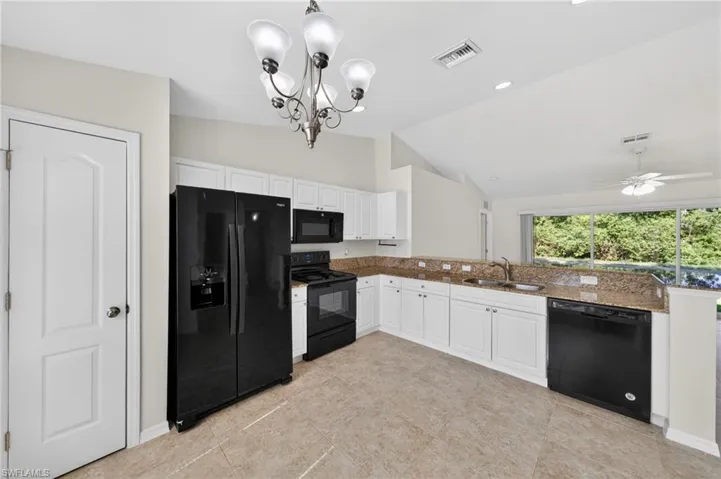 Kitchen featuring white cabinetry, granite countertops, black appliances, and tile flooring