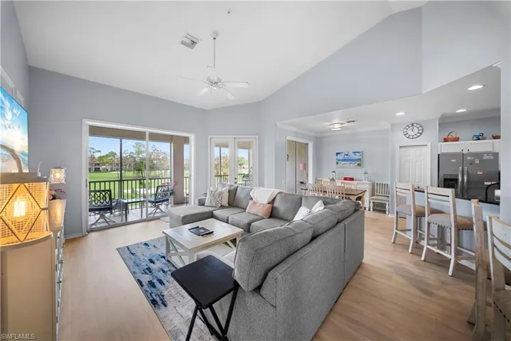 Living room with light wood finished floors, a ceiling fan, lofted ceiling, and ornamental molding