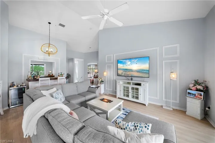 Living room featuring light wood finished floors, a ceiling fan, lofted ceiling, and suspended lighting