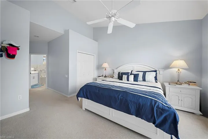 Bedroom featuring light colored carpet, a closet, ceiling fan, and a high ceiling