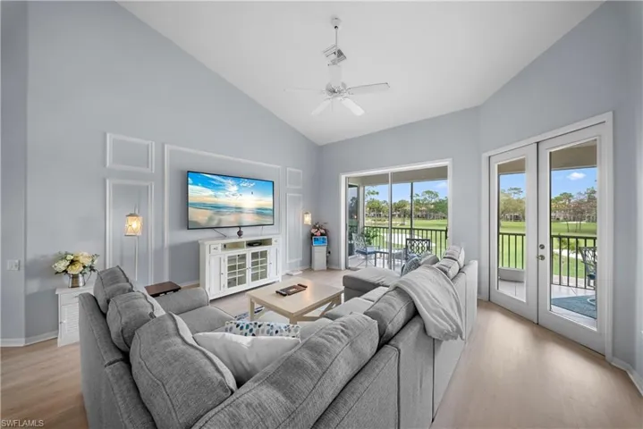 Living room featuring ceiling fan, lofted ceiling, light wood-style flooring, and french doors