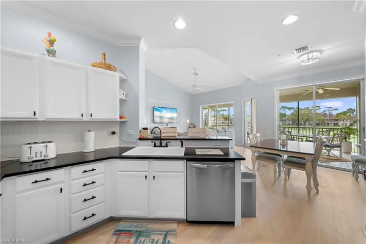 Kitchen featuring crown molding, a peninsula, stainless steel dishwasher, a ceiling fan, and lofted ceiling