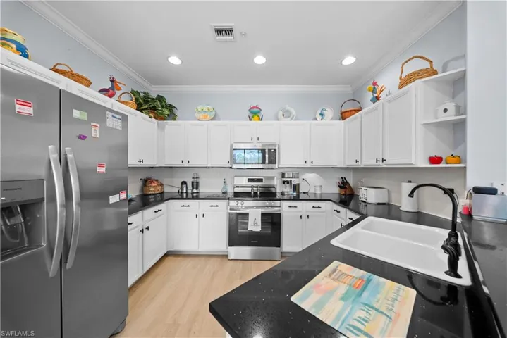 Kitchen featuring stainless steel appliances, open shelves, white cabinets, light wood-style flooring, and ornamental molding