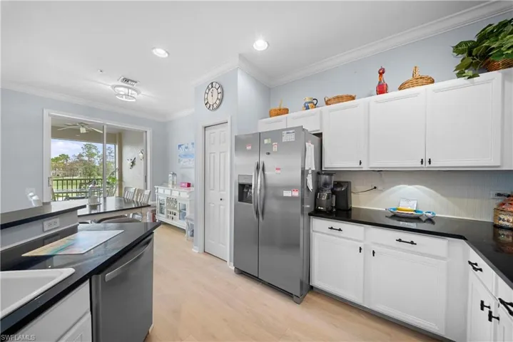 Kitchen featuring ornamental molding, stainless steel appliances, light wood-style floors, white cabinetry, and decorative backsplash