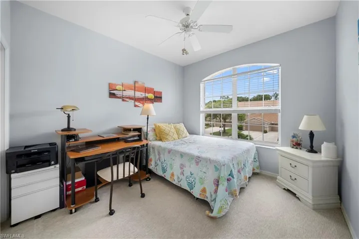 Bedroom featuring light colored carpet, ceiling fan, and a desk