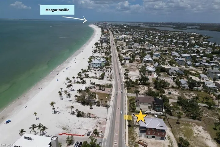 Aerial view of property and surrounding area with waterfront with a beach and nearby suburban area