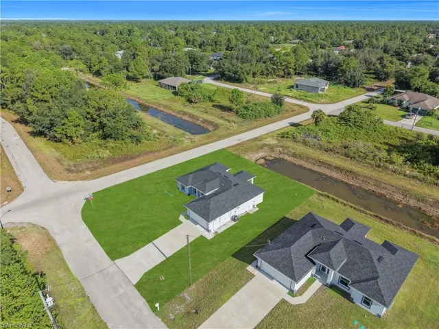 Newly constructed property featuring a dark shingle roof, light-colored exterior, and an attached two-car garage