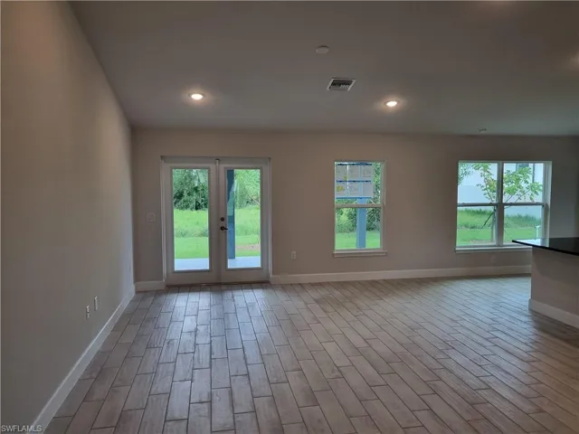 Empty room featuring french doors, hardwood / wood-style floors, and a wealth of natural light