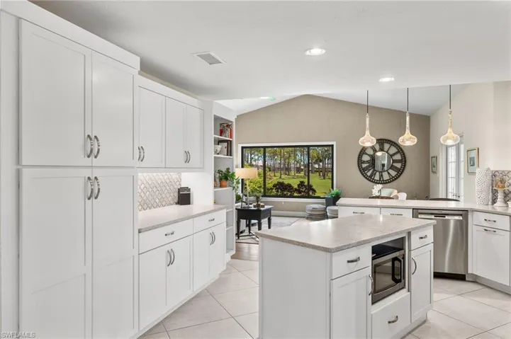 Kitchen featuring appliances with stainless steel finishes, white cabinets, hanging light fixtures, light tile patterned floors, and a kitchen island