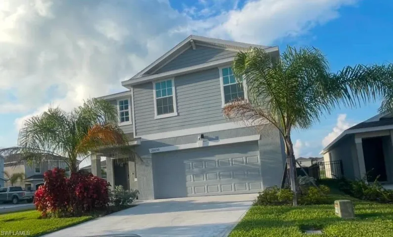 View of front of house with an attached garage, concrete driveway, and a front yard