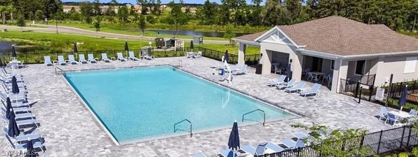 Community pool featuring a patio and view of wooded area