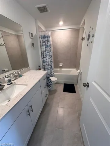 Bathroom featuring vanity, shower / bath combo with shower curtain, and light tile patterned floors