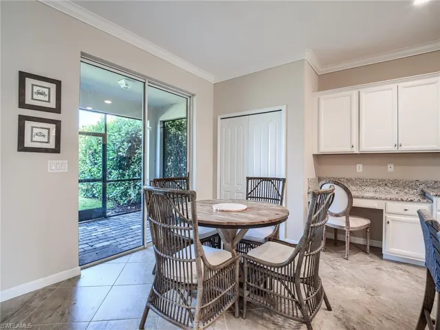 Tiled dining space featuring crown molding and built in desk