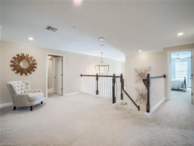 Living area with ceiling fan with notable chandelier, light carpet, and ornamental molding