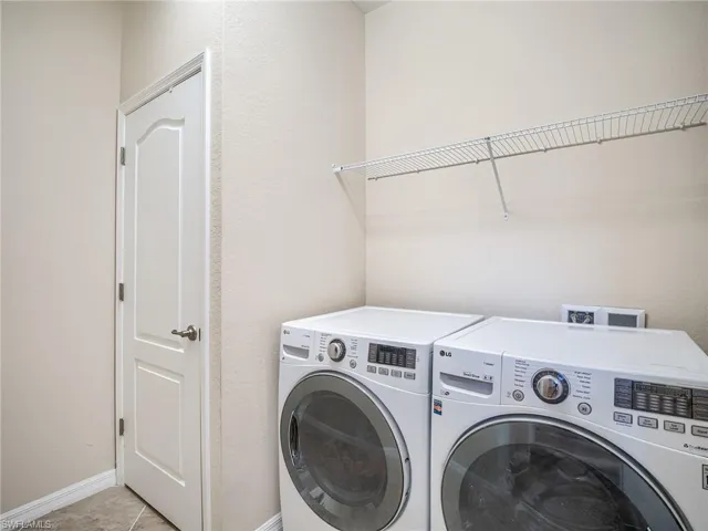 Laundry area with washer and dryer and light tile patterned floors