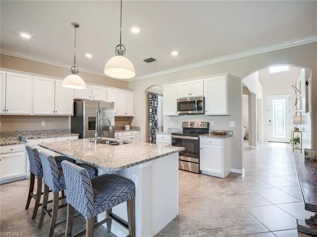 Kitchen with sink, white cabinetry, a kitchen island with sink, and stainless steel appliances