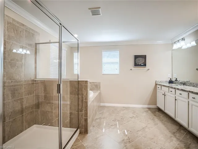 Bathroom featuring independent shower and bath, double vanity, tile floors, and crown molding