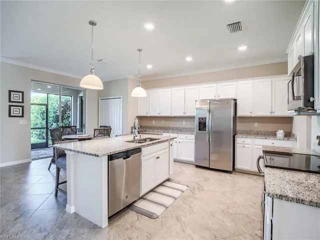 Kitchen featuring appliances with stainless steel finishes, sink, light stone counters, a kitchen island with sink, and light tile patterned flooring