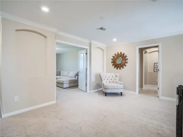 Living area with crown molding and light carpet