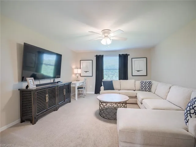Living room featuring light carpet, ceiling fan, and a wealth of natural light
