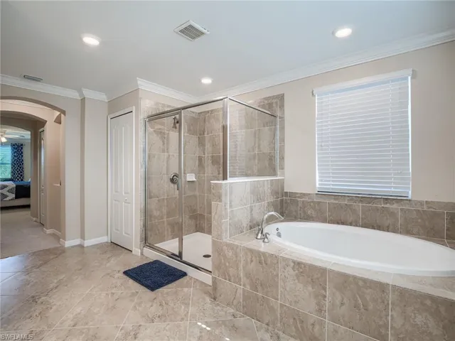 Bathroom featuring shower with separate bathtub, tile patterned floors, and ornamental molding