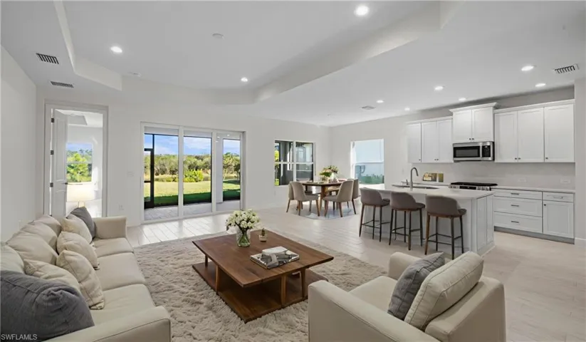 The heart of the home features soaring recessed ceilings, expansive living spaces, and seamless flow between the great room, dining area, and kitchen. Walls of glass frame peaceful preserve views while filling the home with natural light, creating an inviting atmosphere that feels both spacious and comfortable.