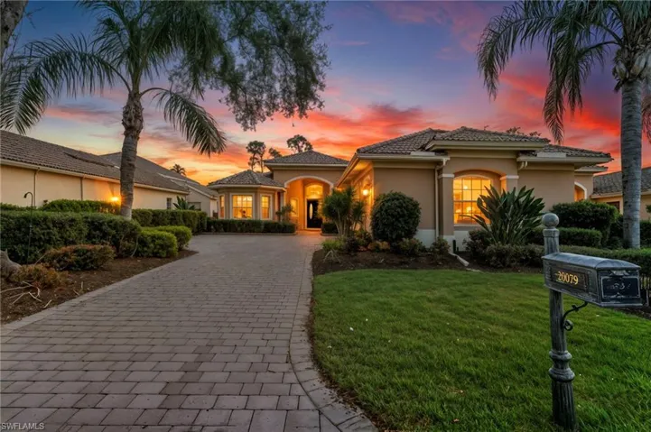 Mediterranean / spanish house with decorative driveway, a lawn, and stucco siding