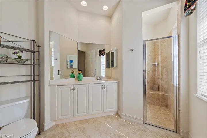 Bathroom featuring a shower stall, vanity, and light marble finish flooring