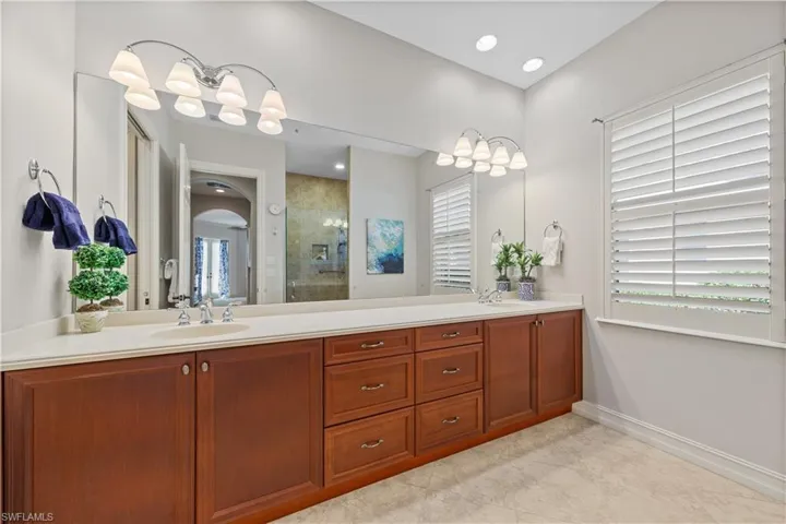 Full bath featuring a tile shower, double vanity, and recessed lighting