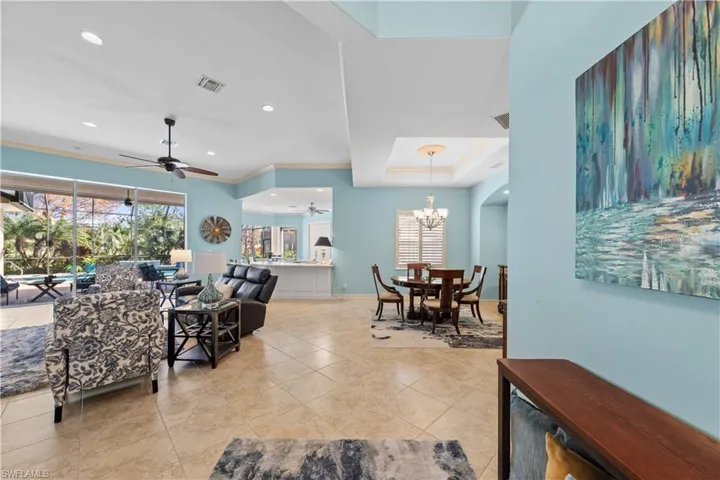 Living room featuring ceiling fan, healthy amount of natural light, light tile patterned floors, suspended lighting, and a tray ceiling