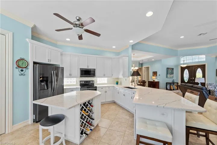 Kitchen with a breakfast bar, white cabinets, a peninsula, light stone countertops, and open floor plan