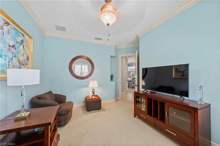 Living area featuring ornamental molding, carpet, and a ceiling fan