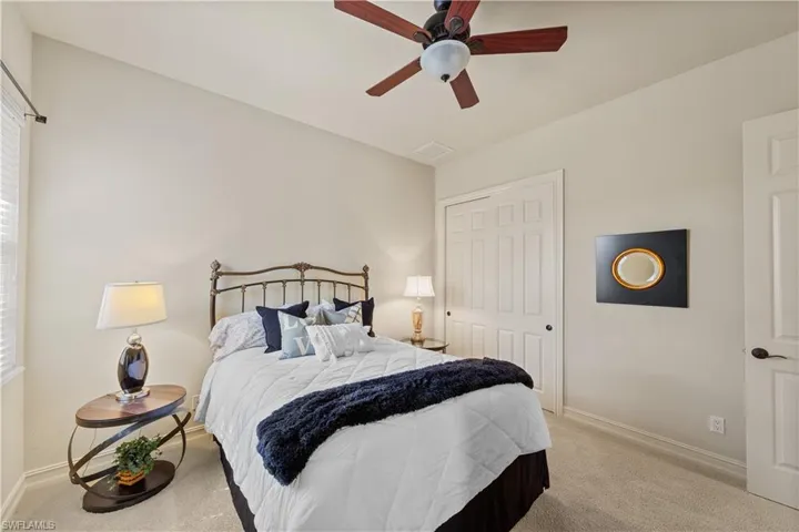 Carpeted bedroom with a ceiling fan and a closet