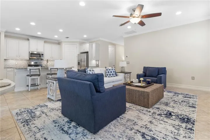 Living room with sink, ceiling fan, crown molding, and light tile patterned floors